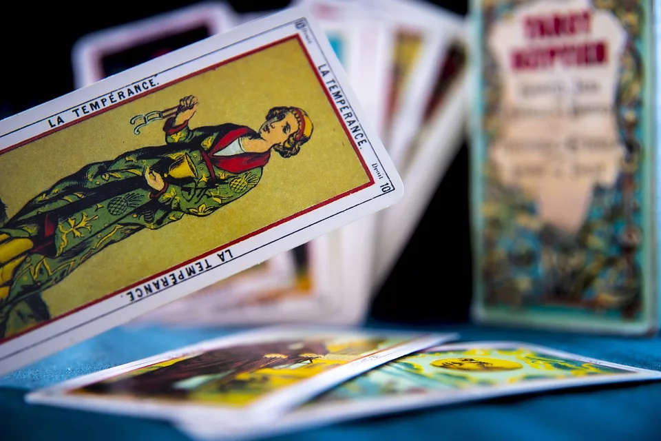 Das Bild zeigt ein Tarot-Deck auf einem Tisch, dessen Karten kunstvoll gestaltet und mit Symbolen und Figuren versehen sind. Die Karten scheinen in einer bestimmten Reihenfolge angeordnet zu sein, was auf eine Tarot-Lesung hindeutet. Tarot-Karten sind ein Werkzeug für spirituelle Praktiken und können helfen, den Geist zu klären und die Intuition zu stärken.